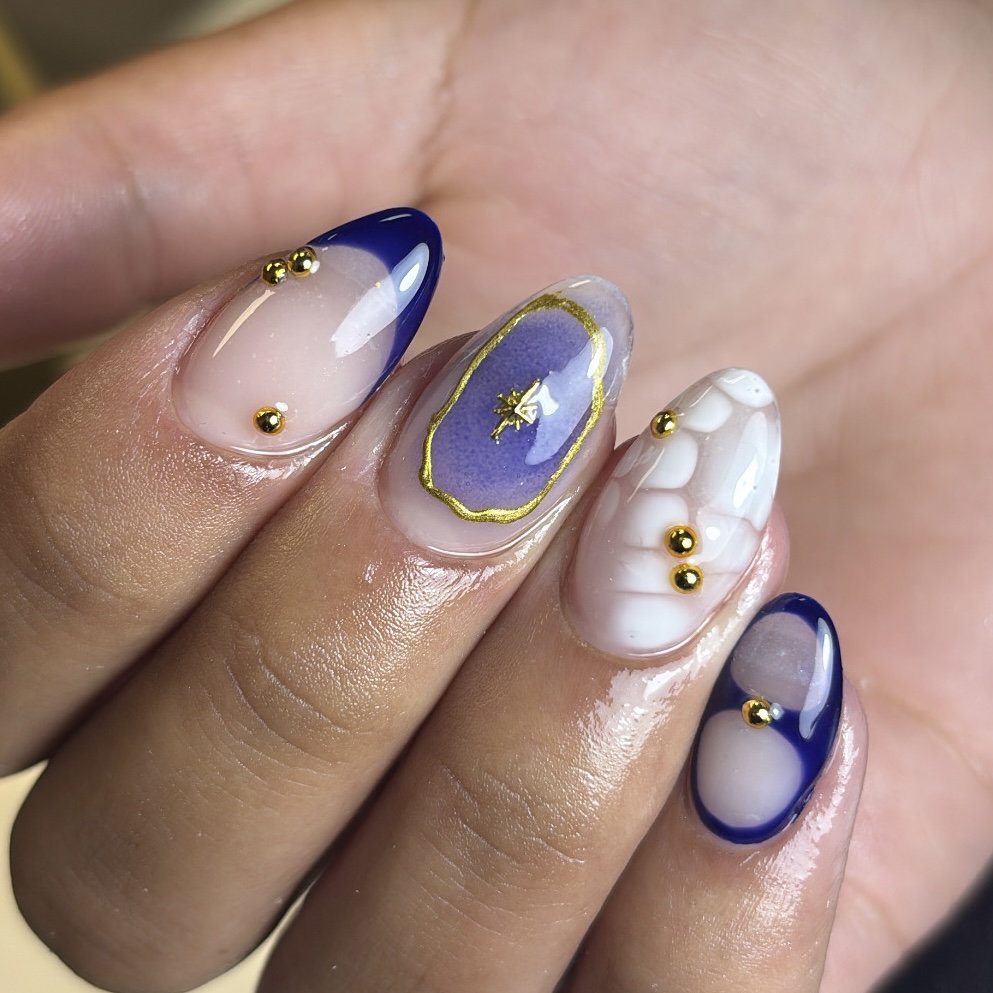 Navy French tips met gouden studs en een paarse accentnagel